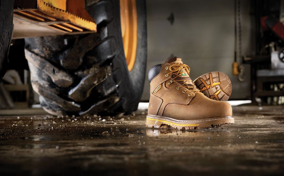 Calgary Commercial Photography. Work boots on display next to construction vehicle in the garage.